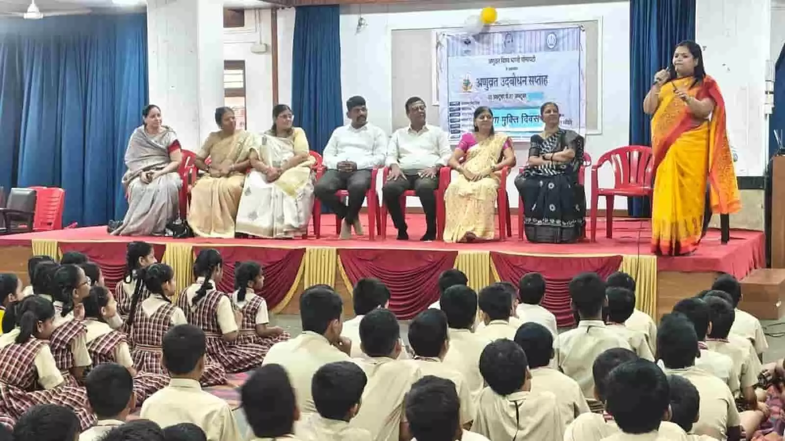तस्वीर में मंच पर बैठे अतिथि और सामने जमीन पर बैठे स्कूली बच्चे दिखाई दे रहे हैं। तस्वीर में मंच पर बैठे अतिथि और सामने जमीन पर बैठे स्कूली बच्चे दिखाई दे रहे हैं।