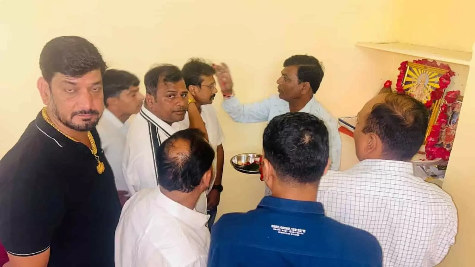 तस्वीर में कमरे के भीतर देवी प्रतिमा के सामने खड़े लोग पूजा-अर्चना के दौरान तिलक लगवाते दिख रहे हैं। तस्वीर में कमरे के भीतर देवी प्रतिमा के सामने खड़े लोग पूजा-अर्चना के दौरान तिलक लगवाते दिख रहे हैं।