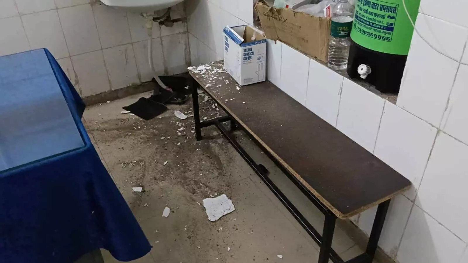 तस्वीर में अस्पताल के एक कमरे में फर्श और लकड़ी की बेंच पर छत का प्लास्टर गिरा हुआ दिखाई दे रहा है। तस्वीर में अस्पताल के एक कमरे में फर्श और लकड़ी की बेंच पर छत का प्लास्टर गिरा हुआ दिखाई दे रहा है।