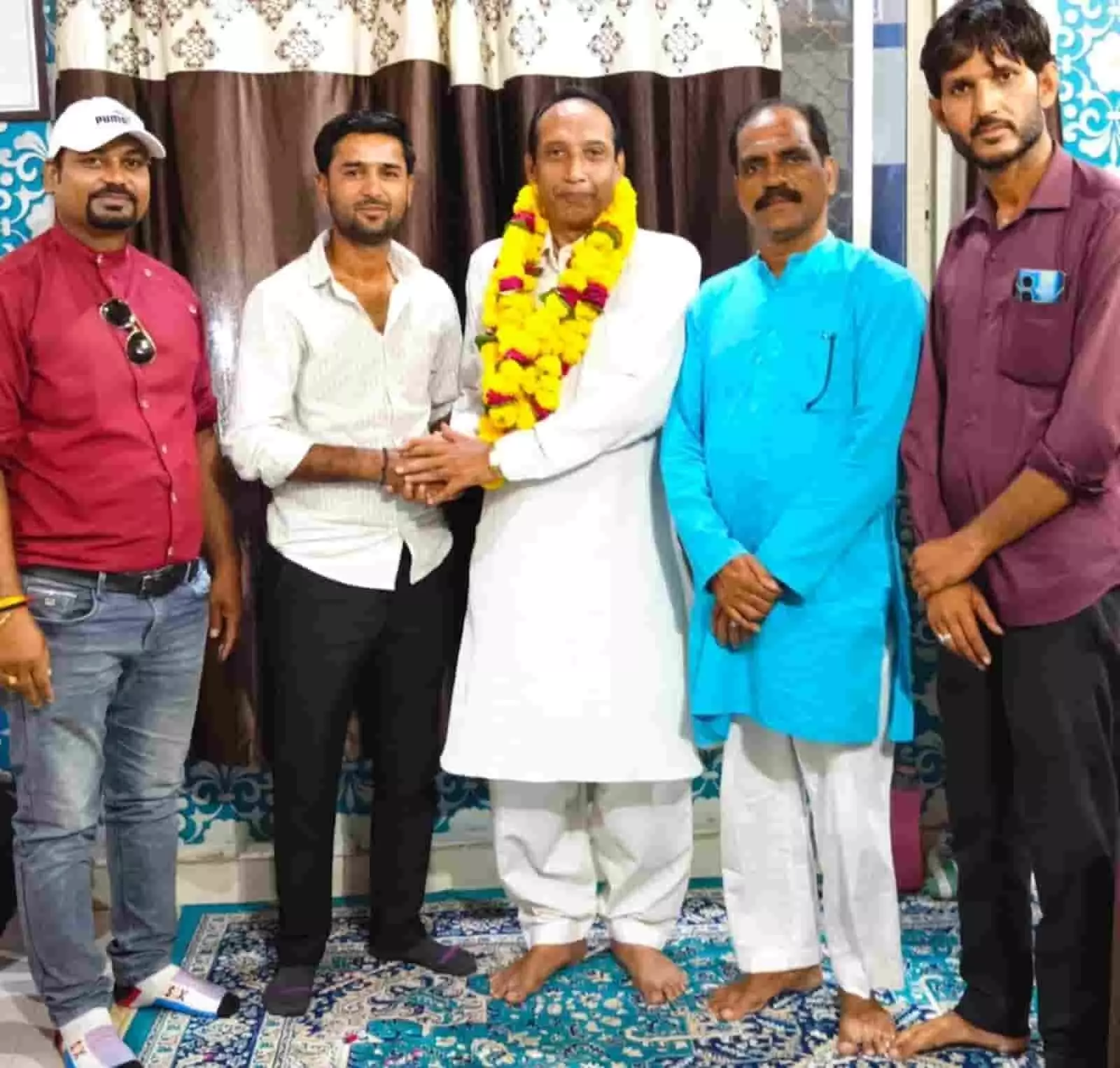 तस्वीर में दिख रही पांच लोगों की टोली में, बीच में खड़े व्यक्ति को गेंदे की माला पहनाकर अन्य लोग उनका अभिनंदन कर रहे हैं। तस्वीर में दिख रही पांच लोगों की टोली में, बीच में खड़े व्यक्ति को गेंदे की माला पहनाकर अन्य लोग उनका अभिनंदन कर रहे हैं।