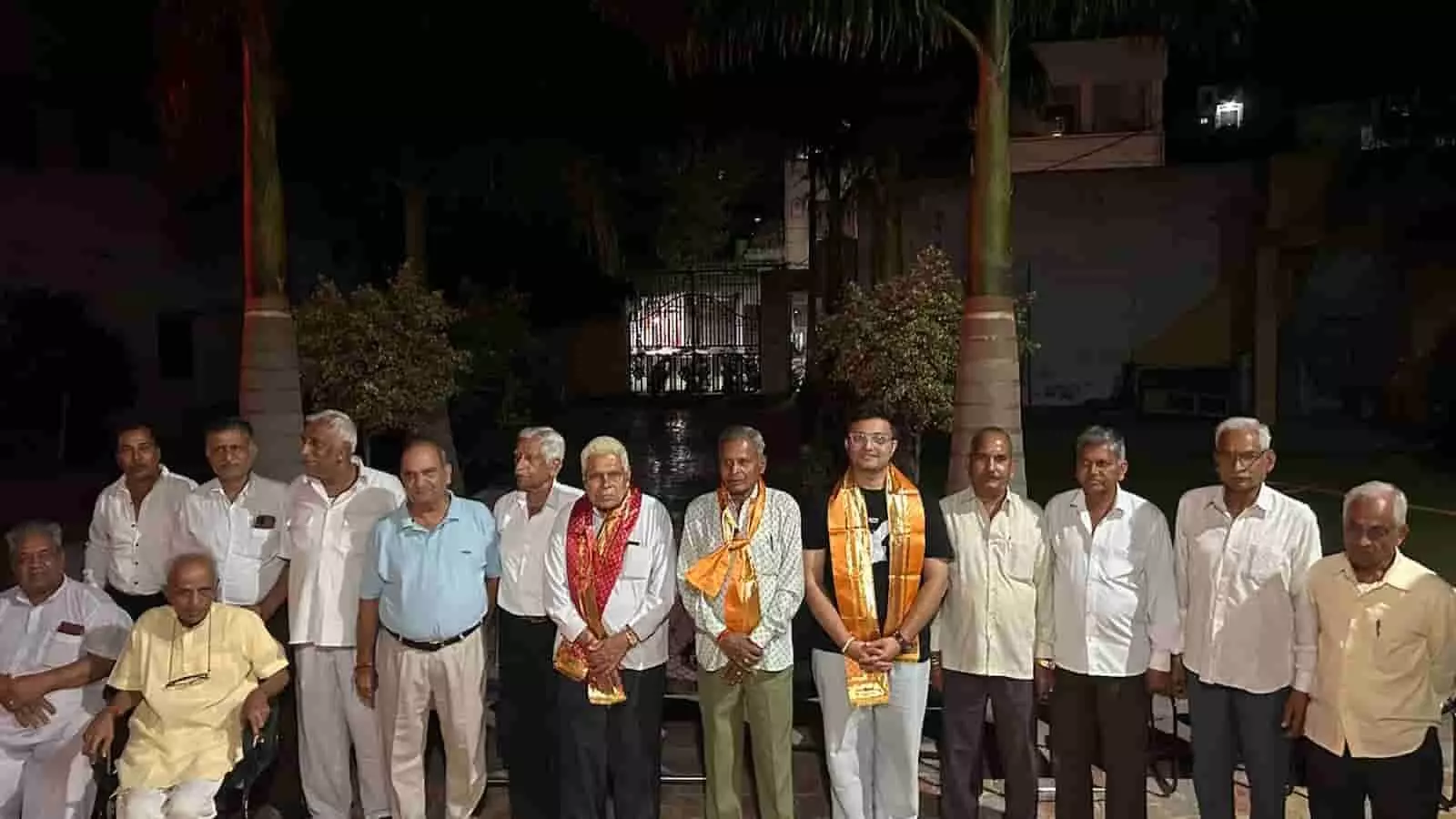 तस्वीर में दिख रहे वरिष्ठ जन और अन्य लोग रात के समय एक साथ खड़े होकर मुस्कुरा रहे हैं। तस्वीर में दिख रहे वरिष्ठ जन और अन्य लोग रात के समय एक साथ खड़े होकर मुस्कुरा रहे हैं।