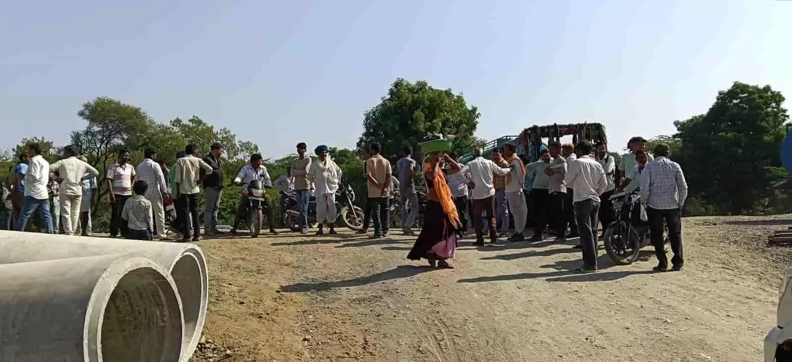 तस्वीर में ग्रामीण कच्चे रास्ते पर सीमेंट के पाइपों के पास खड़े होकर प्रदर्शन कर रहे हैं। तस्वीर में ग्रामीण कच्चे रास्ते पर सीमेंट के पाइपों के पास खड़े होकर प्रदर्शन कर रहे हैं।