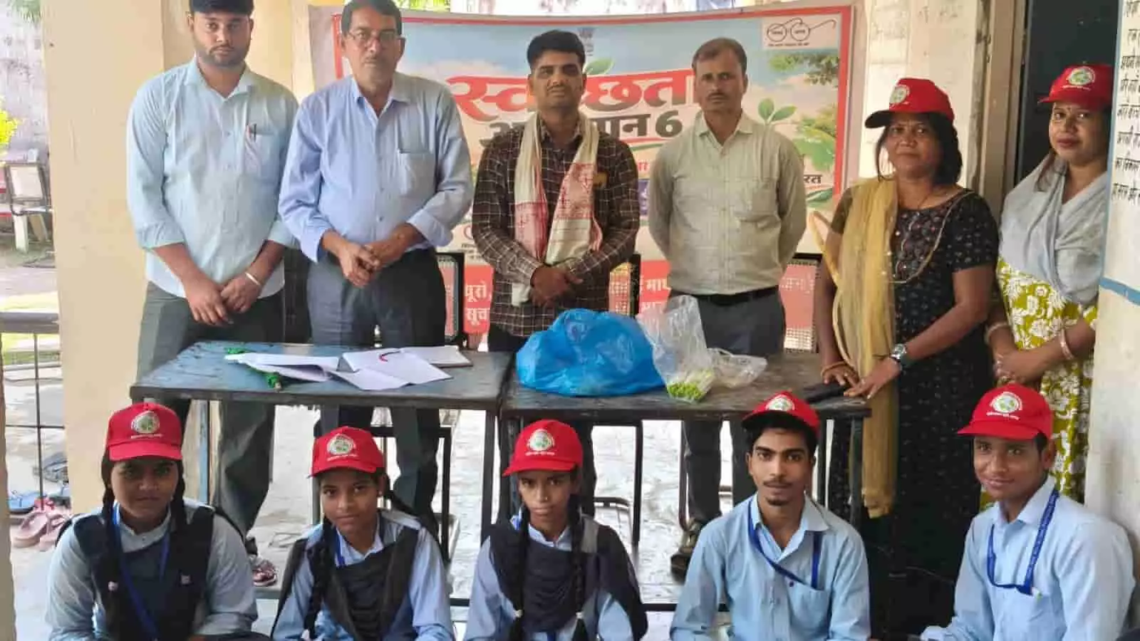 तस्वीर में लाल टोपी पहने विद्यार्थी आगे बैठे हैं और पीछे शिक्षक तथा अधिकारी खड़े हैं। तस्वीर में लाल टोपी पहने विद्यार्थी आगे बैठे हैं और पीछे शिक्षक तथा अधिकारी खड़े हैं।