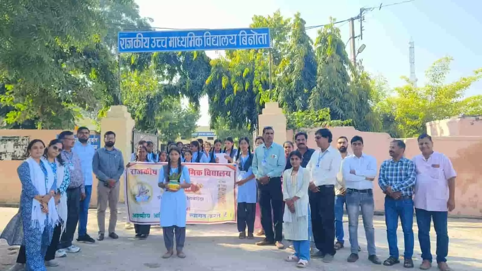 तस्वीर में दिख रही छात्रा हाथ में कलश लिए विद्यालय परिसर के मुख्य द्वार पर साथी छात्रों और अध्यापकों के साथ खड़ी है। तस्वीर में दिख रही छात्रा हाथ में कलश लिए विद्यालय परिसर के मुख्य द्वार पर साथी छात्रों और अध्यापकों के साथ खड़ी है।