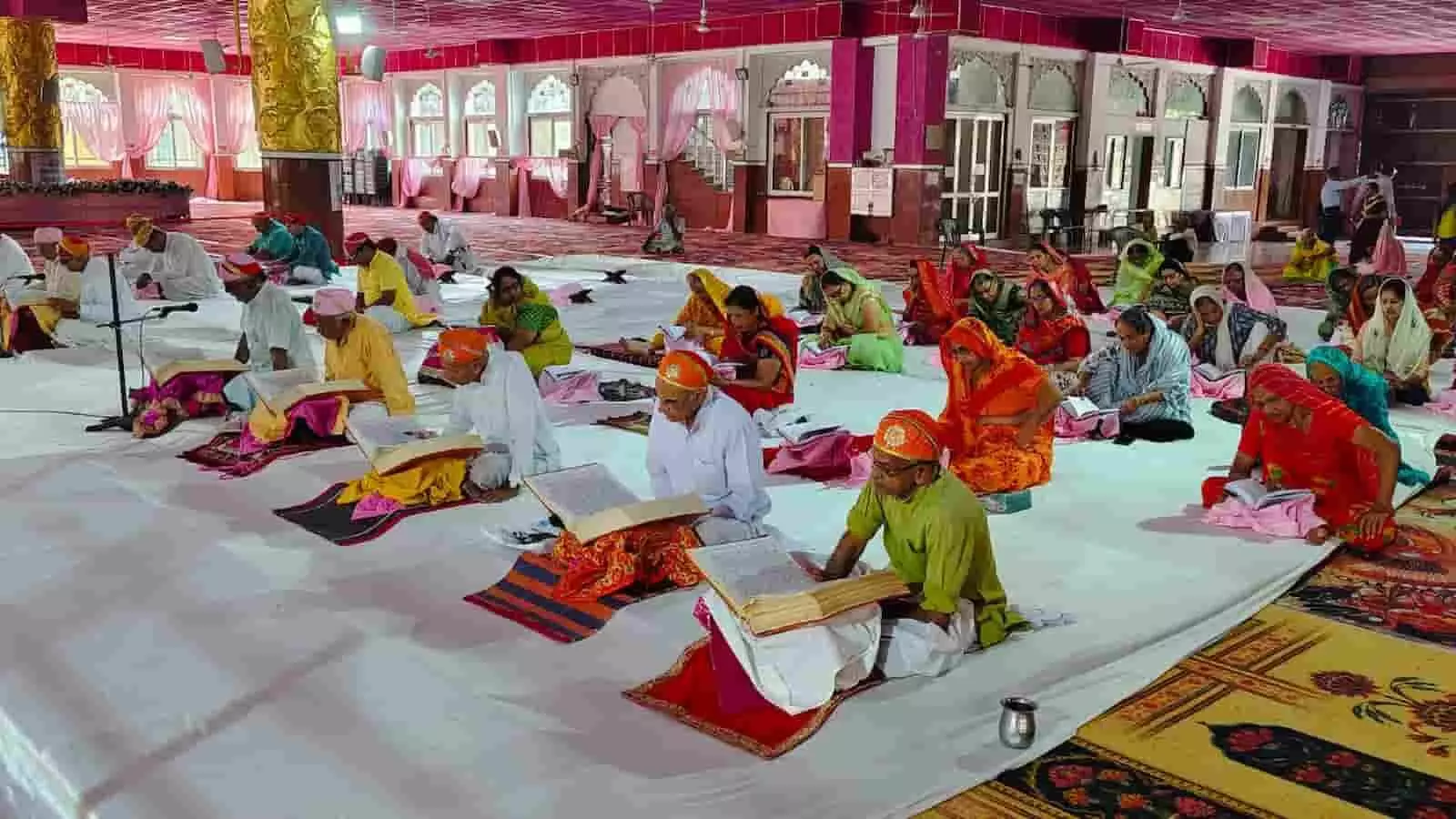 तस्वीर में दिख रही एक बड़े हॉल की फर्श पर बैठकर धार्मिक ग्रंथ का सामूहिक पाठ करते श्रद्धालु। तस्वीर में दिख रही एक बड़े हॉल की फर्श पर बैठकर धार्मिक ग्रंथ का सामूहिक पाठ करते श्रद्धालु।