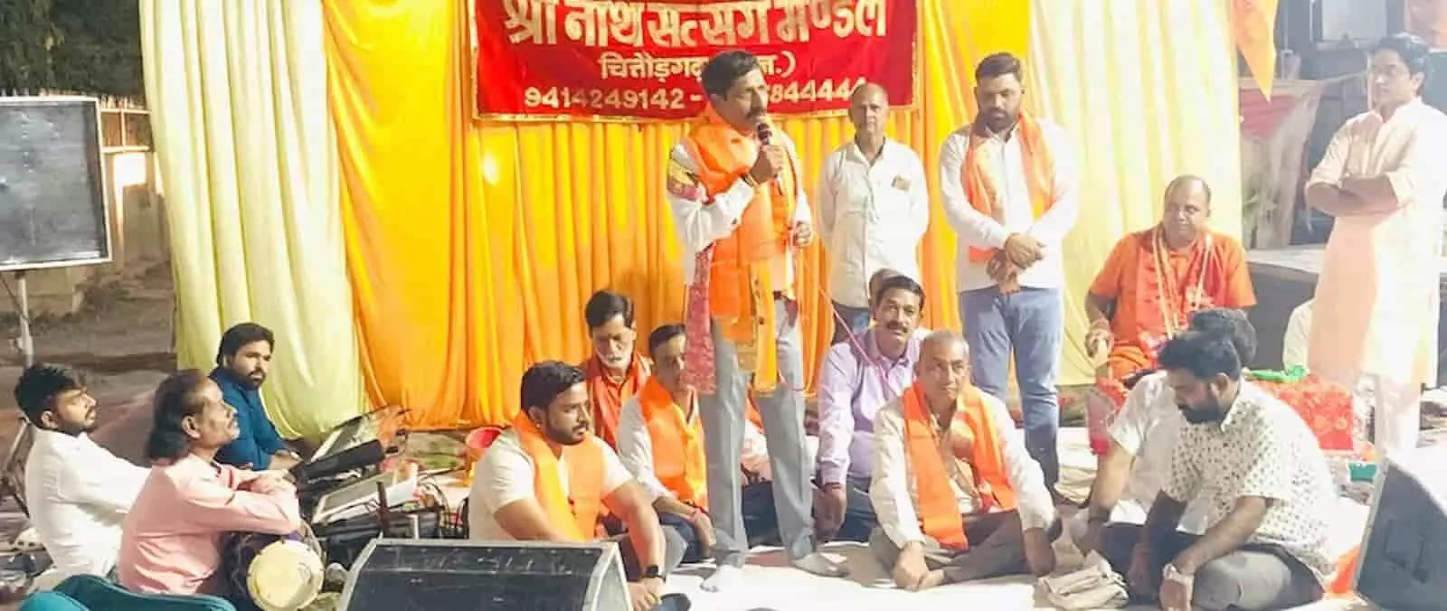 तस्वीर में केसरिया उपरना पहने एक व्यक्ति मंच पर माइक से सभा को संबोधित कर रहा है। तस्वीर में केसरिया उपरना पहने एक व्यक्ति मंच पर माइक से सभा को संबोधित कर रहा है।
