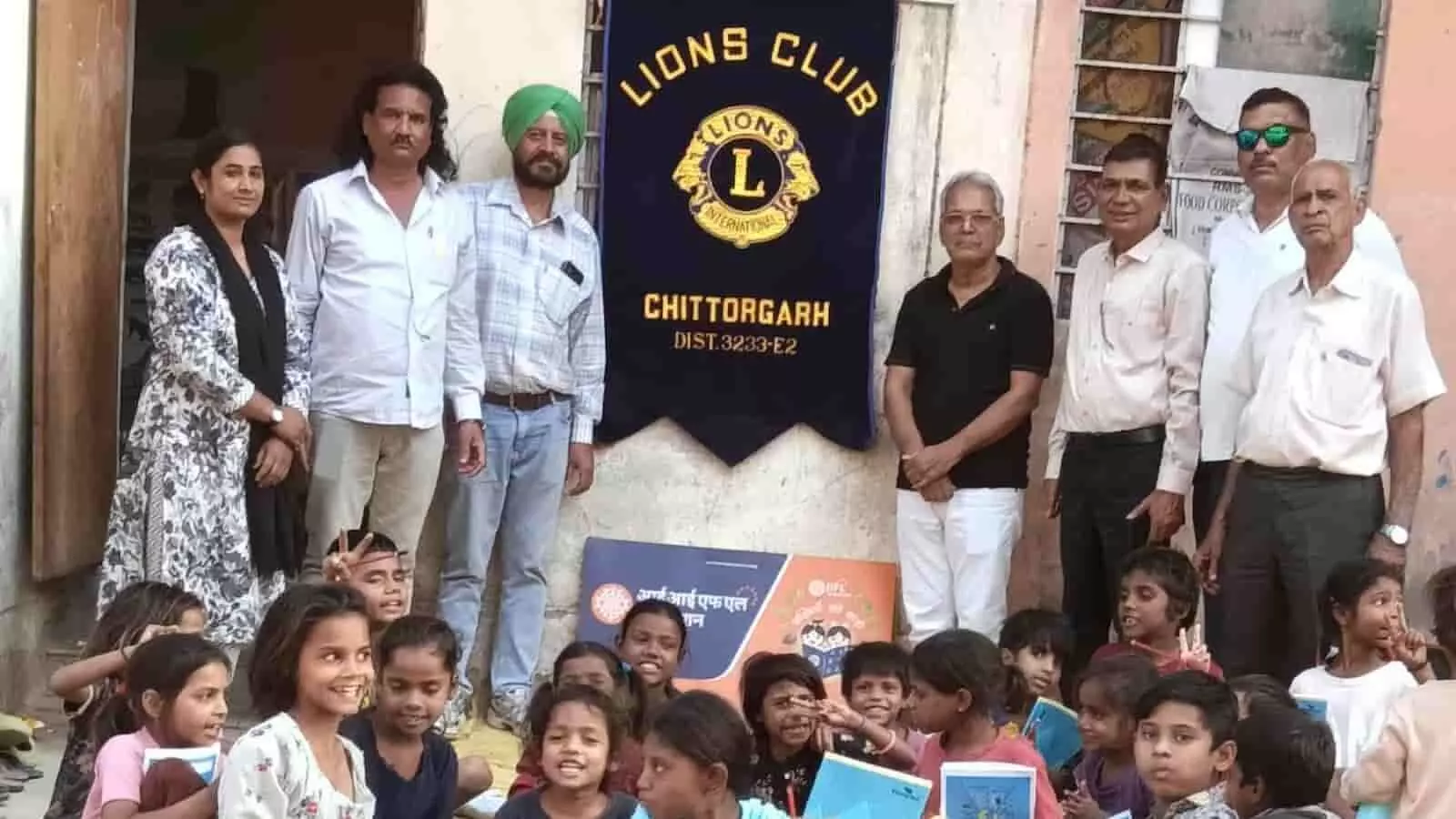 तस्वीर में लायंस क्लब के बैनर के नीचे खड़े पदाधिकारी और नीचे बैठीं बच्चे किताबें पकड़े दिख रहे हैं। तस्वीर में लायंस क्लब के बैनर के नीचे खड़े पदाधिकारी और नीचे बैठीं बच्चे किताबें पकड़े दिख रहे हैं।
