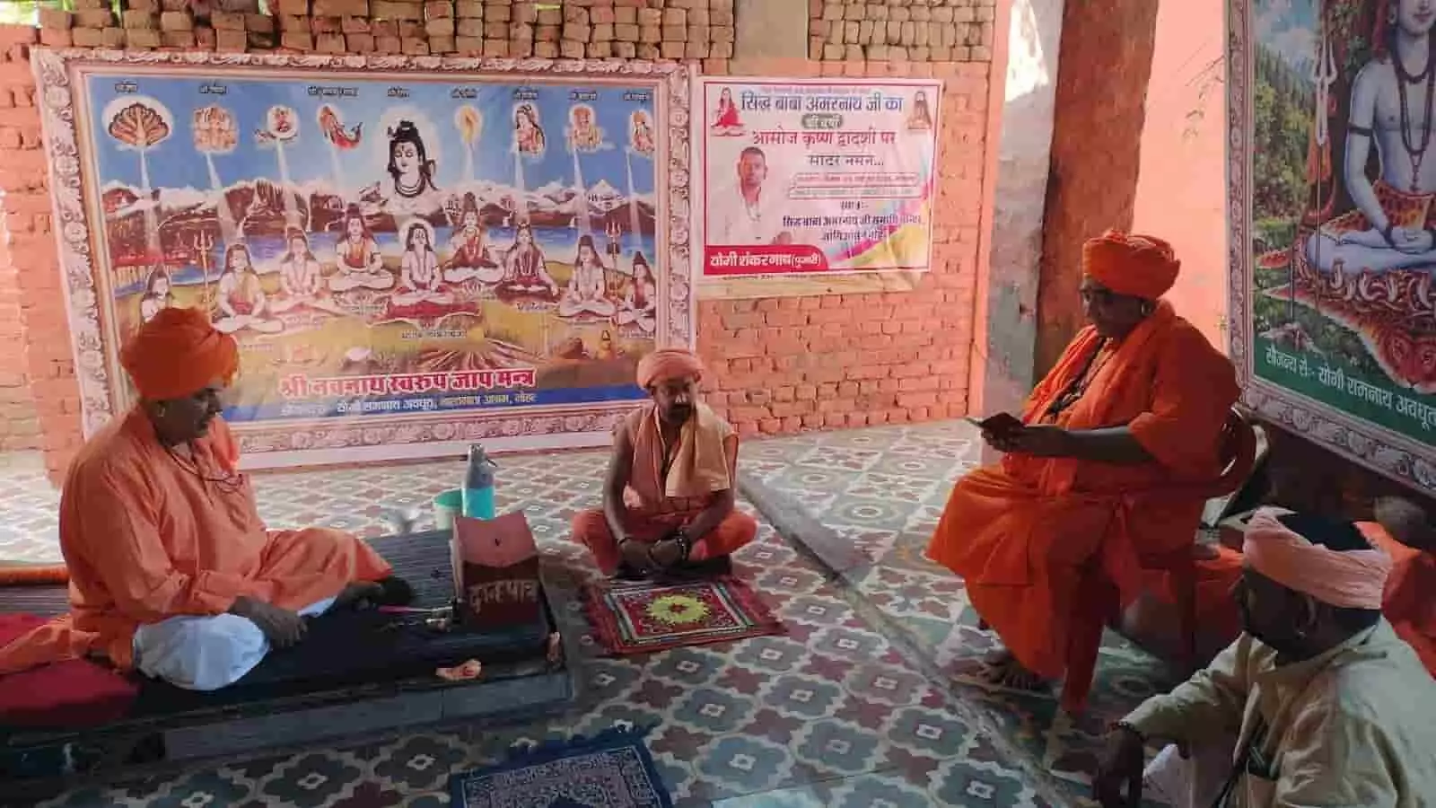 तस्वीर में दिख रही धार्मिक तस्वीरों के सामने महंत और संत जमीन एवं कुर्सी पर बैठे हैं। तस्वीर में दिख रही धार्मिक तस्वीरों के सामने महंत और संत जमीन एवं कुर्सी पर बैठे हैं।