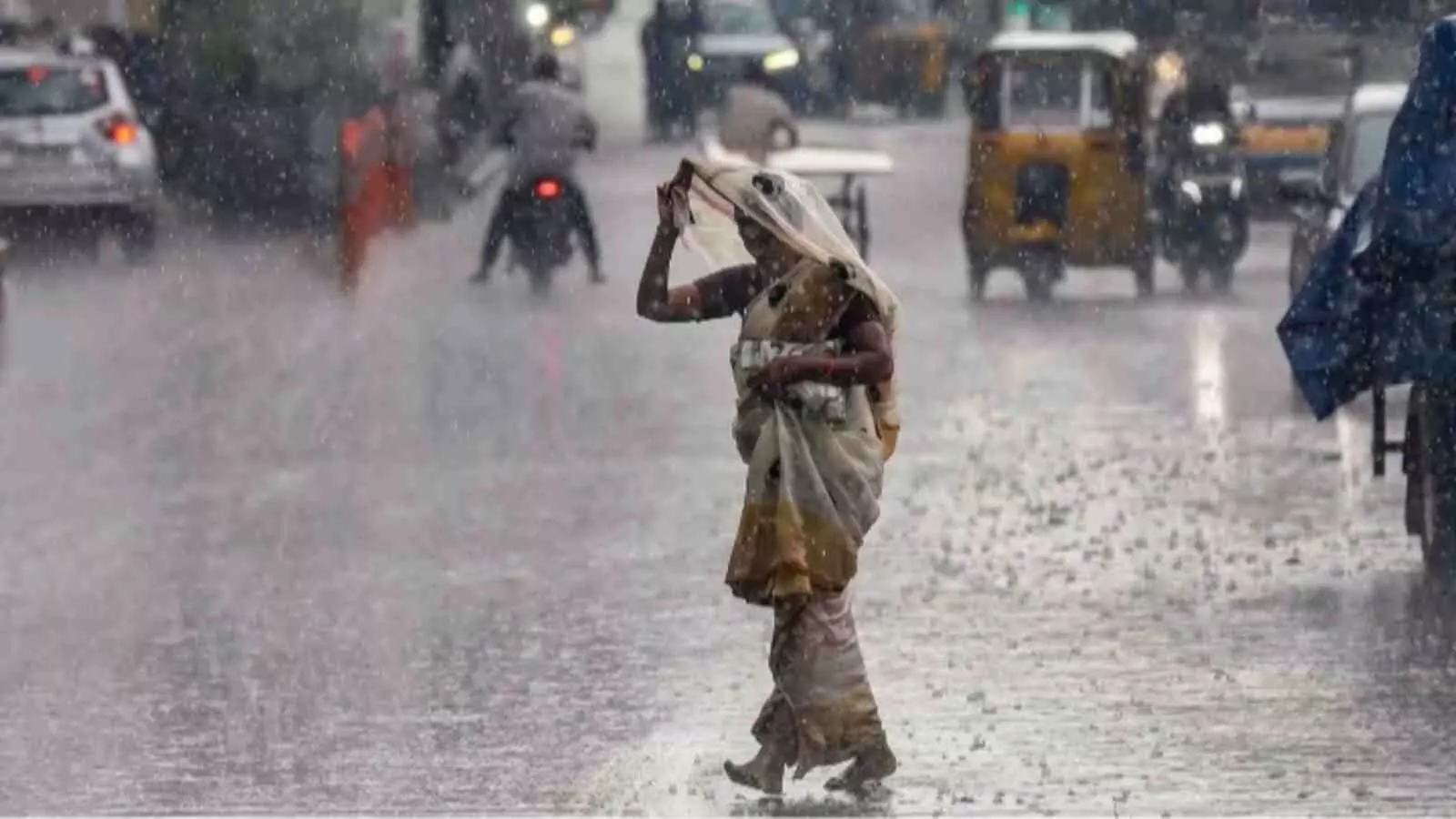 सड़क पर जलभराव और भारी बारिश के बीच से गुजरती महिला| सड़क पर जलभराव और भारी बारिश के बीच से गुजरती महिला|