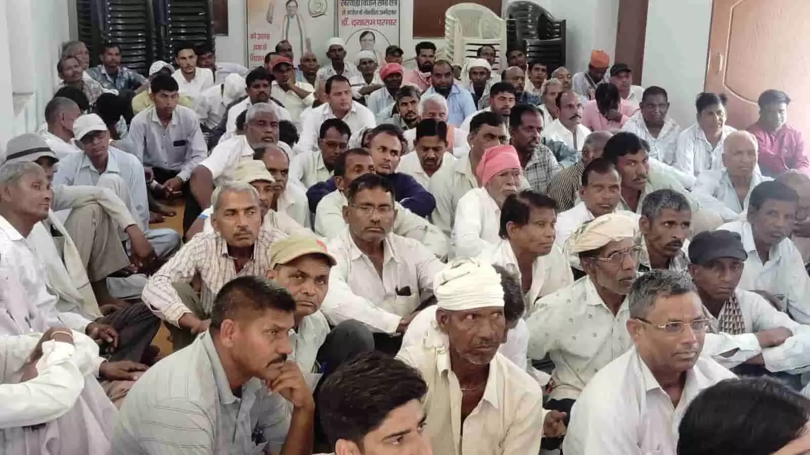 तस्वीर में दिख रही सभा में कई लोग एक हॉल में जमीन पर बैठकर बैठक सुन रहे हैं। तस्वीर में दिख रही सभा में कई लोग एक हॉल में जमीन पर बैठकर बैठक सुन रहे हैं।
