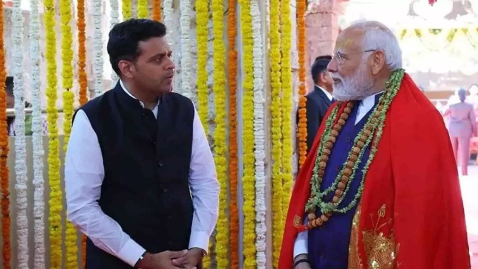 तस्वीर में फूलों से सजे परिसर में खड़े होकर धनराज नथवानी और प्रधानमंत्री नरेन्द्र मोदी आमने-सामने बातचीत कर रहे हैं। तस्वीर में फूलों से सजे परिसर में खड़े होकर धनराज नथवानी और प्रधानमंत्री नरेन्द्र मोदी आमने-सामने बातचीत कर रहे हैं।