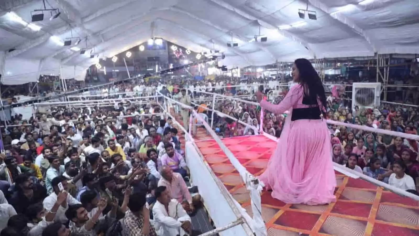 तस्वीर में दिख रही कलाकार मंच पर नृत्य कर रही हैं और सामने बैठी भीड़ उन्हें देख रही है। तस्वीर में दिख रही कलाकार मंच पर नृत्य कर रही हैं और सामने बैठी भीड़ उन्हें देख रही है।