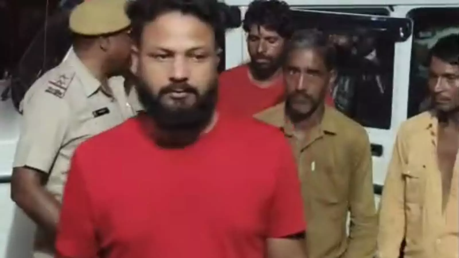 तस्वीर में पुलिस वाहन के सामने वर्दीधारी पुलिसकर्मी और हिरासत में लिए गए आरोपी खड़े दिख रहे हैं। तस्वीर में पुलिस वाहन के सामने वर्दीधारी पुलिसकर्मी और हिरासत में लिए गए आरोपी खड़े दिख रहे हैं।