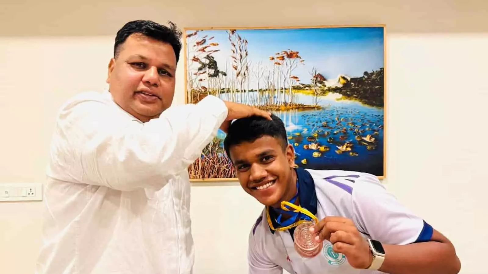 तस्वीर में बाईं ओर खड़े पंकज चौधरी दाईं ओर पदक लिए मुस्कुरा रहे पद्मनाभ चौधरी के सिर पर हाथ रखे हैं। तस्वीर में बाईं ओर खड़े पंकज चौधरी दाईं ओर पदक लिए मुस्कुरा रहे पद्मनाभ चौधरी के सिर पर हाथ रखे हैं।