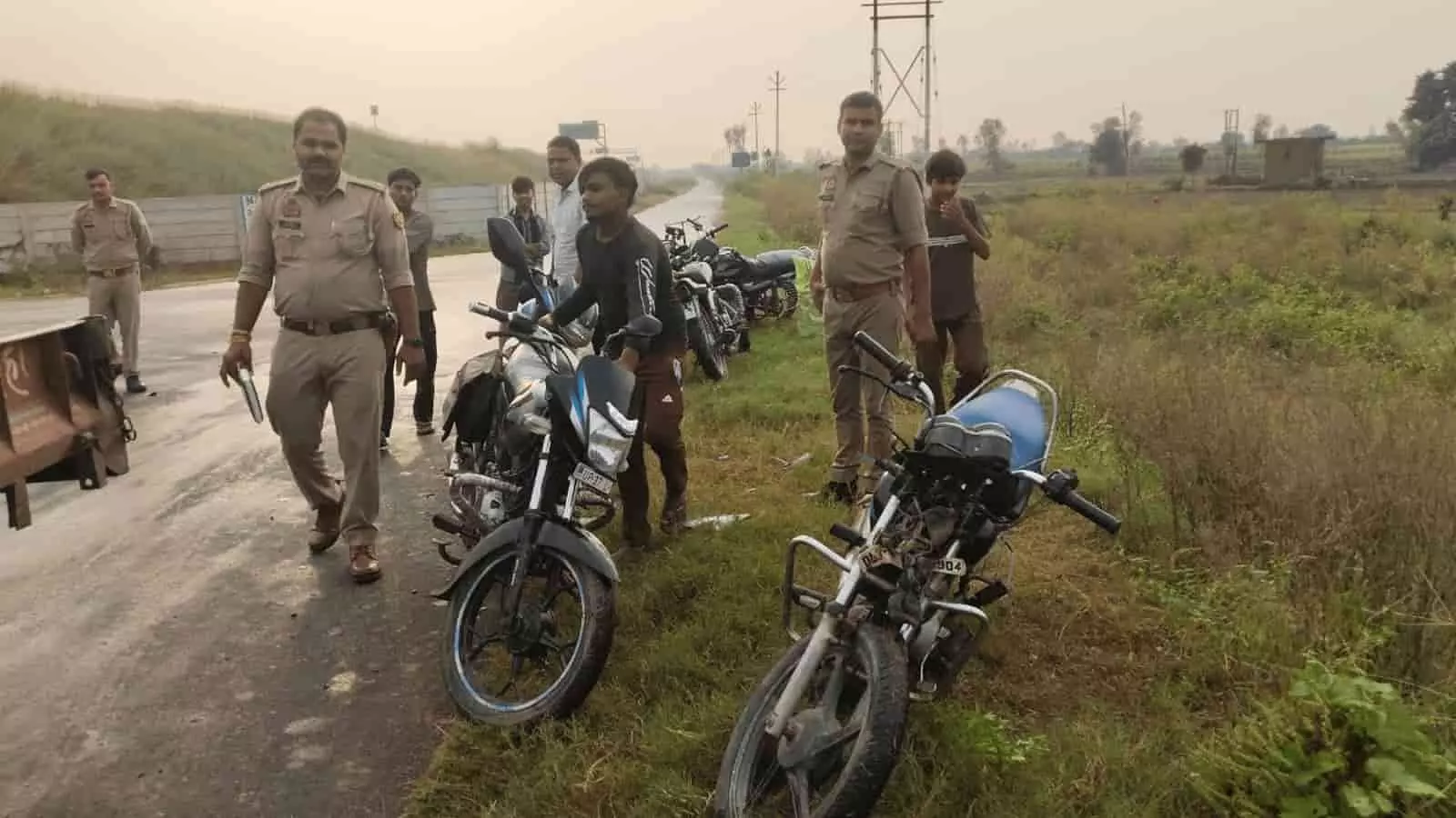 तस्वीर में सड़क किनारे खड़ी क्षतिग्रस्त मोटरसाइकिल और पूछताछ करते हुए पुलिसकर्मी दिखाई दे रहे हैं। तस्वीर में सड़क किनारे खड़ी क्षतिग्रस्त मोटरसाइकिल और पूछताछ करते हुए पुलिसकर्मी दिखाई दे रहे हैं।