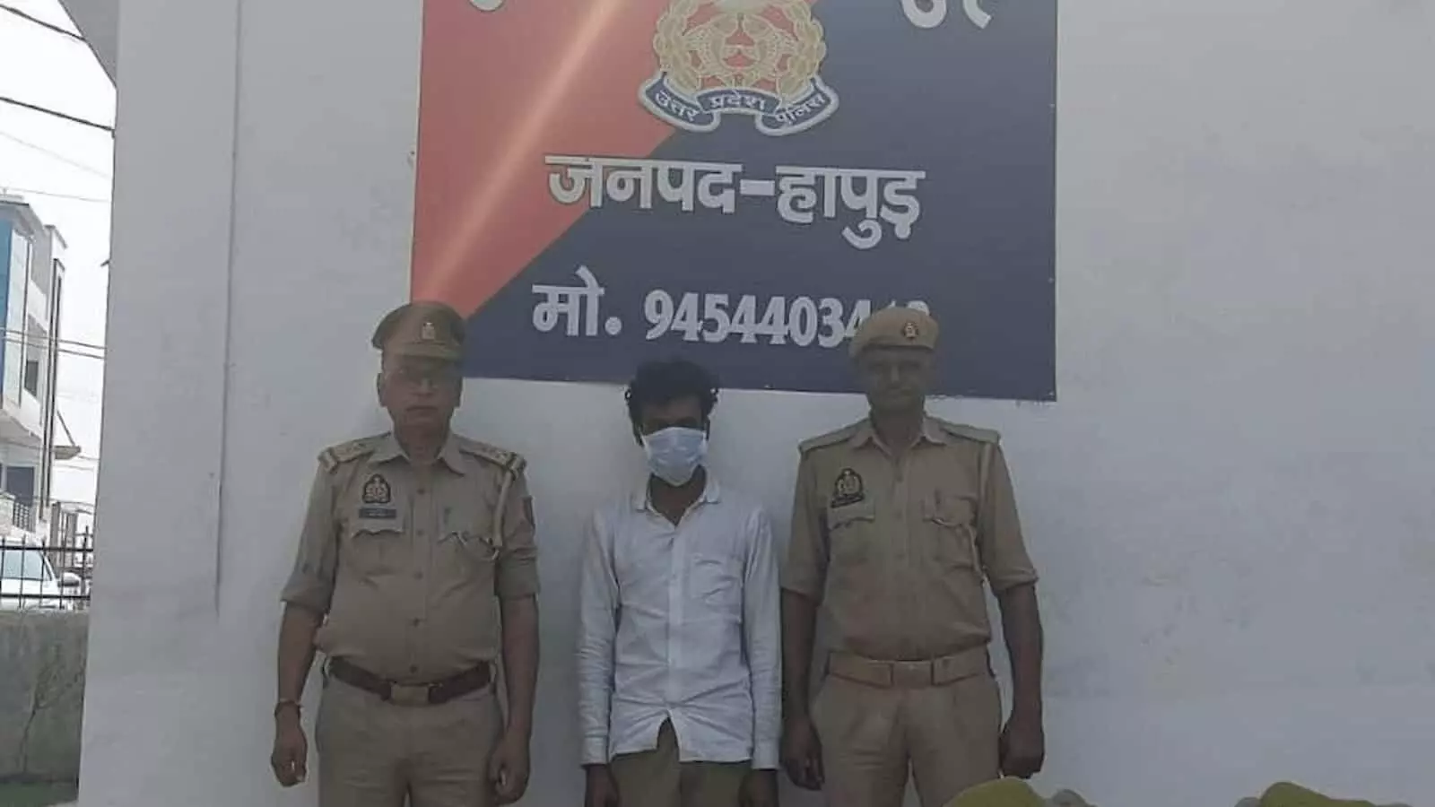 तस्वीर में दोनों तरफ पुलिसकर्मियों के बीच खड़े मास्क पहने हुए आरोपी व्यक्ति दिखाई दे रहे हैं। तस्वीर में दोनों तरफ पुलिसकर्मियों के बीच खड़े मास्क पहने हुए आरोपी व्यक्ति दिखाई दे रहे हैं।