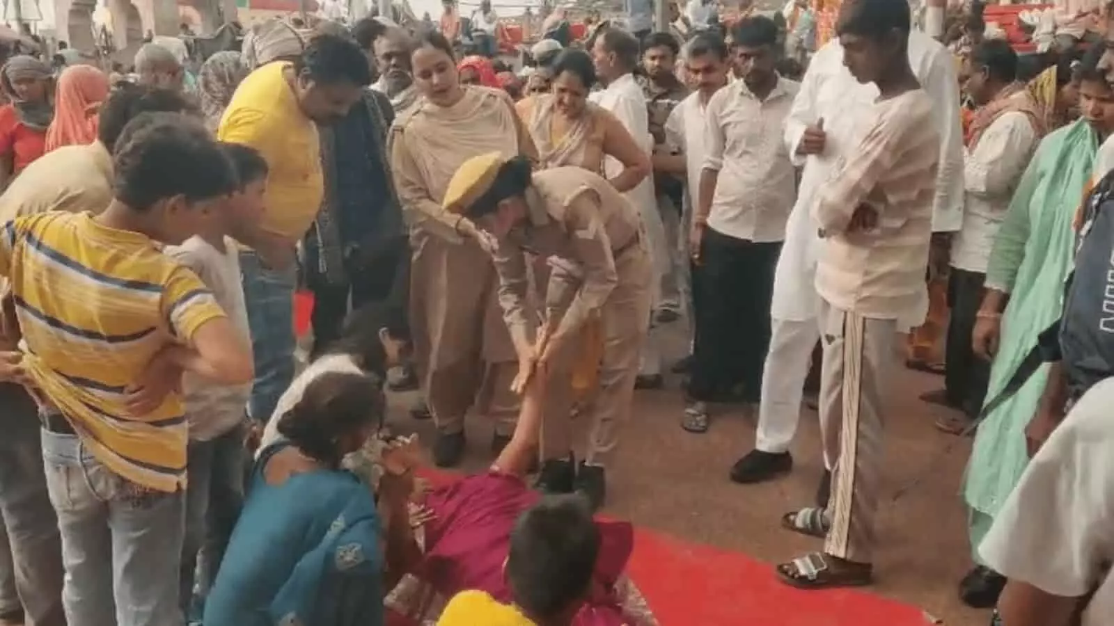 तस्वीर में श्रद्धालुओं की भीड़ के बीच जमीन पर लेटी हुई महिला की देखभाल करती हुई दो महिला पुलिसकर्मी दिखाई दे रही हैं। JPEG तस्वीर में श्रद्धालुओं की भीड़ के बीच जमीन पर लेटी हुई महिला की देखभाल करती हुई दो महिला पुलिसकर्मी दिखाई दे रही हैं। JPEG