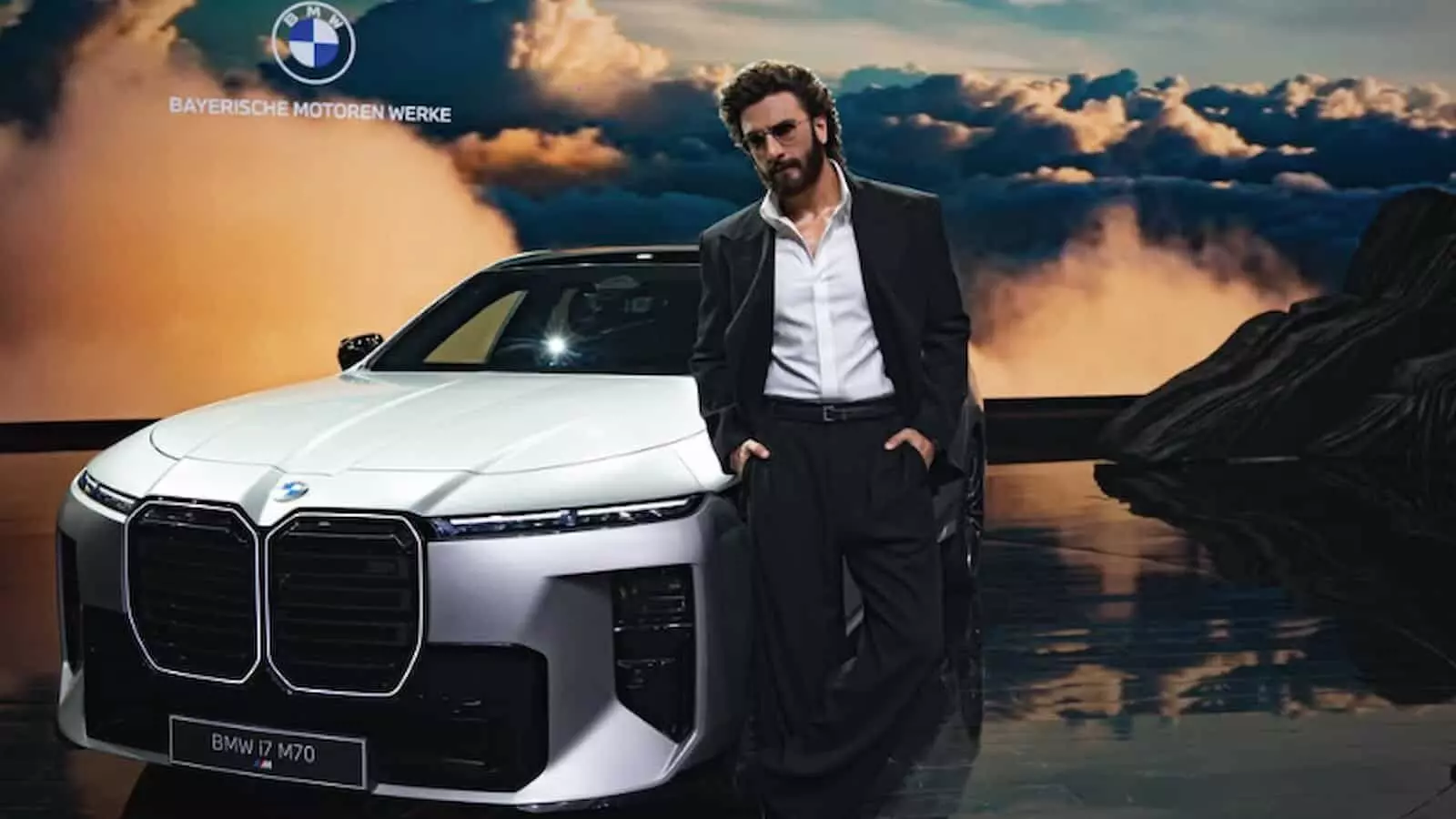 तस्वीर में रणवीर सिंह कार्यक्रम मंच पर लग्जरी इलेक्ट्रिक सेडान BMW i7 कार के पास खड़े हैं। तस्वीर में रणवीर सिंह कार्यक्रम मंच पर लग्जरी इलेक्ट्रिक सेडान BMW i7 कार के पास खड़े हैं।
