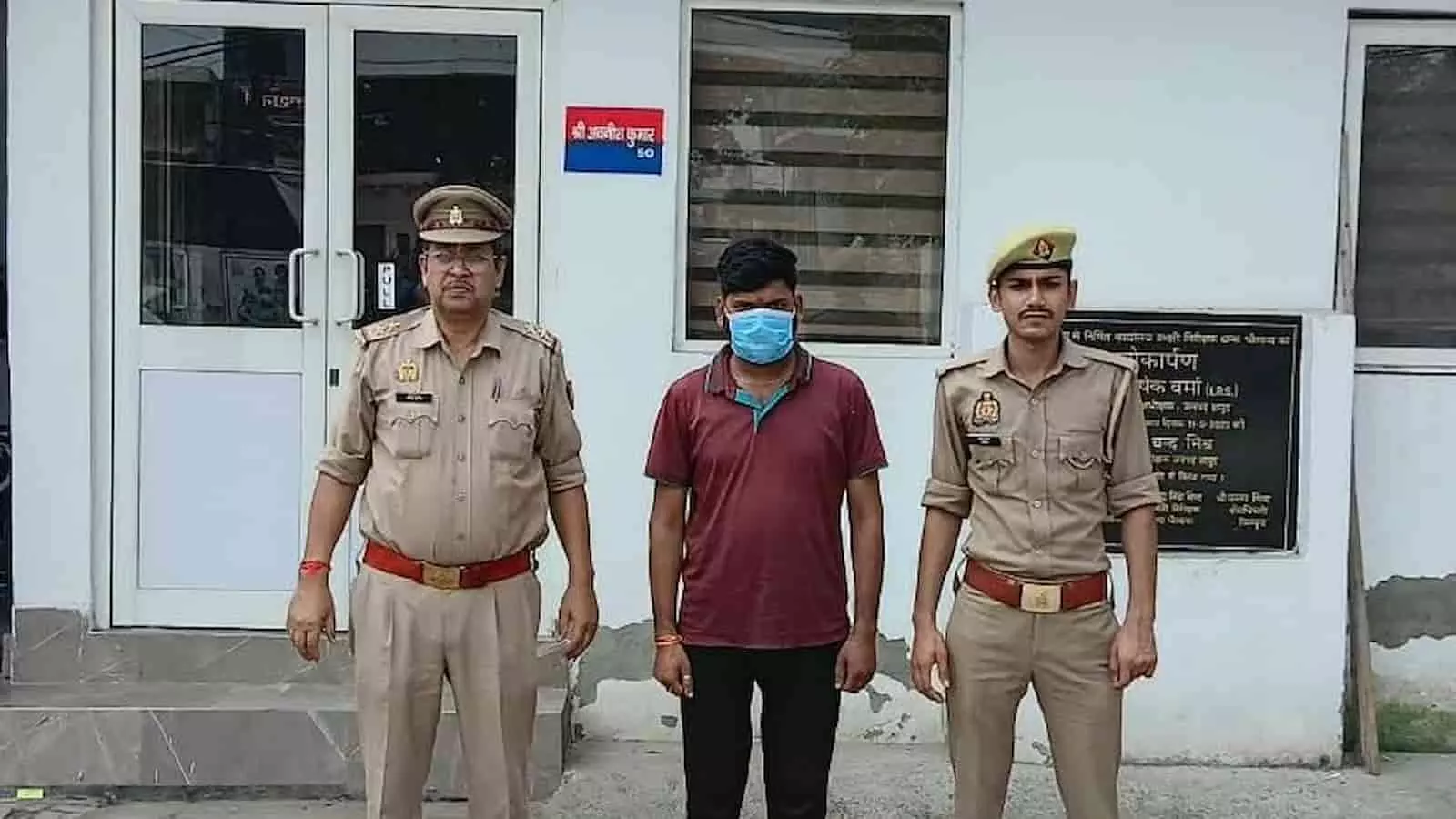 तस्वीर में बाएं से दाएं दो पुलिसकर्मियों के बीच में पुलिस कस्टडी में खड़ा एक शख्स दिख रहा है। तस्वीर में बाएं से दाएं दो पुलिसकर्मियों के बीच में पुलिस कस्टडी में खड़ा एक शख्स दिख रहा है।