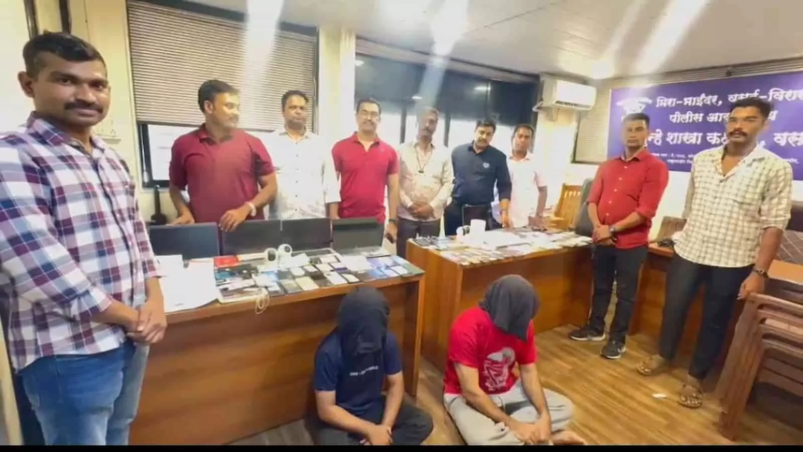 तस्वीर में मीरा-भाईंदर पुलिस यूनिट के अधिकारी कार्यालय में टेबल पर रखी जब्त इलेक्ट्रॉनिक सामग्री के साथ खड़े हैं। तस्वीर में मीरा-भाईंदर पुलिस यूनिट के अधिकारी कार्यालय में टेबल पर रखी जब्त इलेक्ट्रॉनिक सामग्री के साथ खड़े हैं।