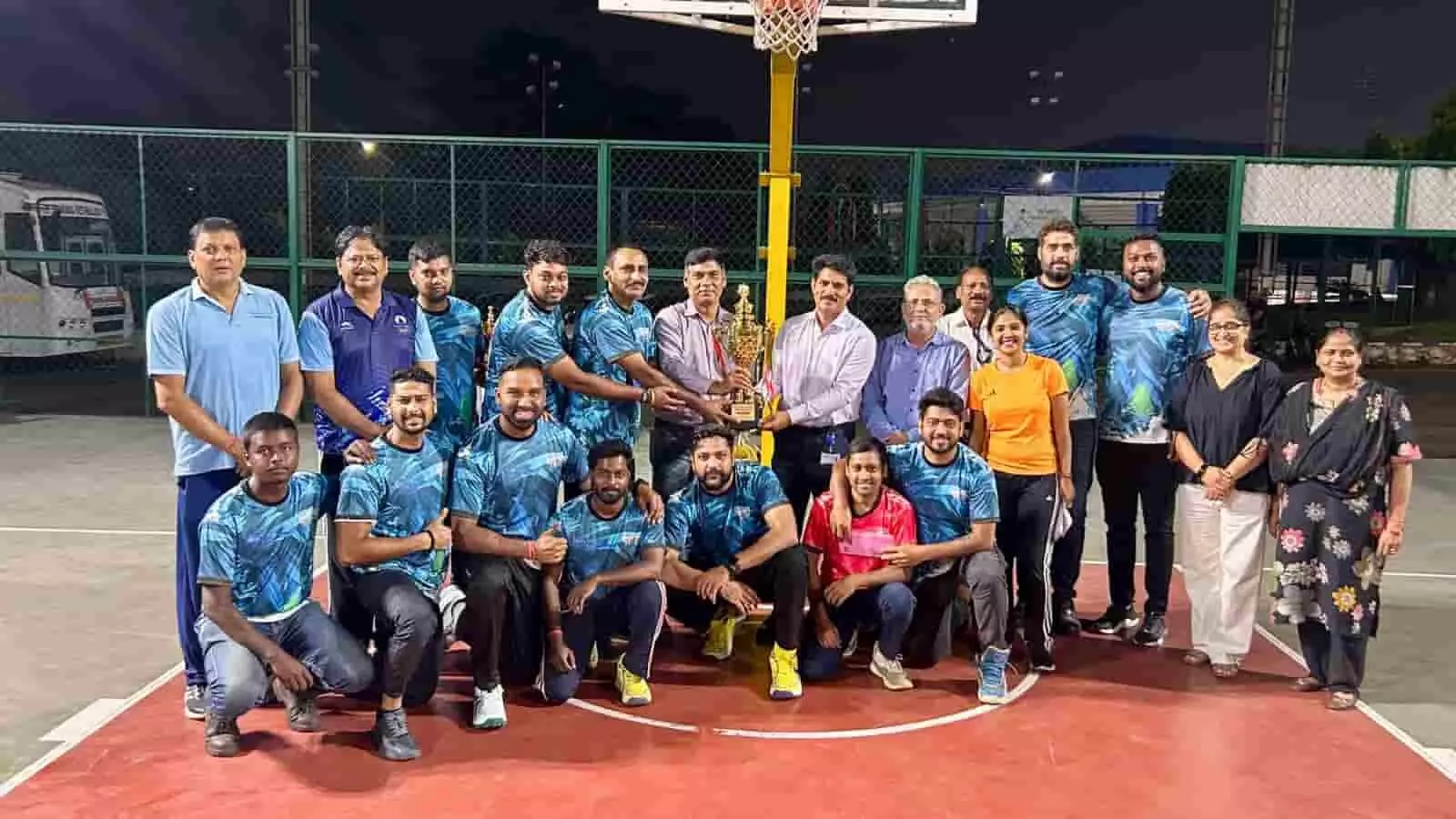 तस्वीर में बास्केटबॉल कोर्ट पर ट्रॉफी पकड़े खिलाड़ी और अतिथि समूह के रूप में पोज दे रहे हैं। तस्वीर में बास्केटबॉल कोर्ट पर ट्रॉफी पकड़े खिलाड़ी और अतिथि समूह के रूप में पोज दे रहे हैं।