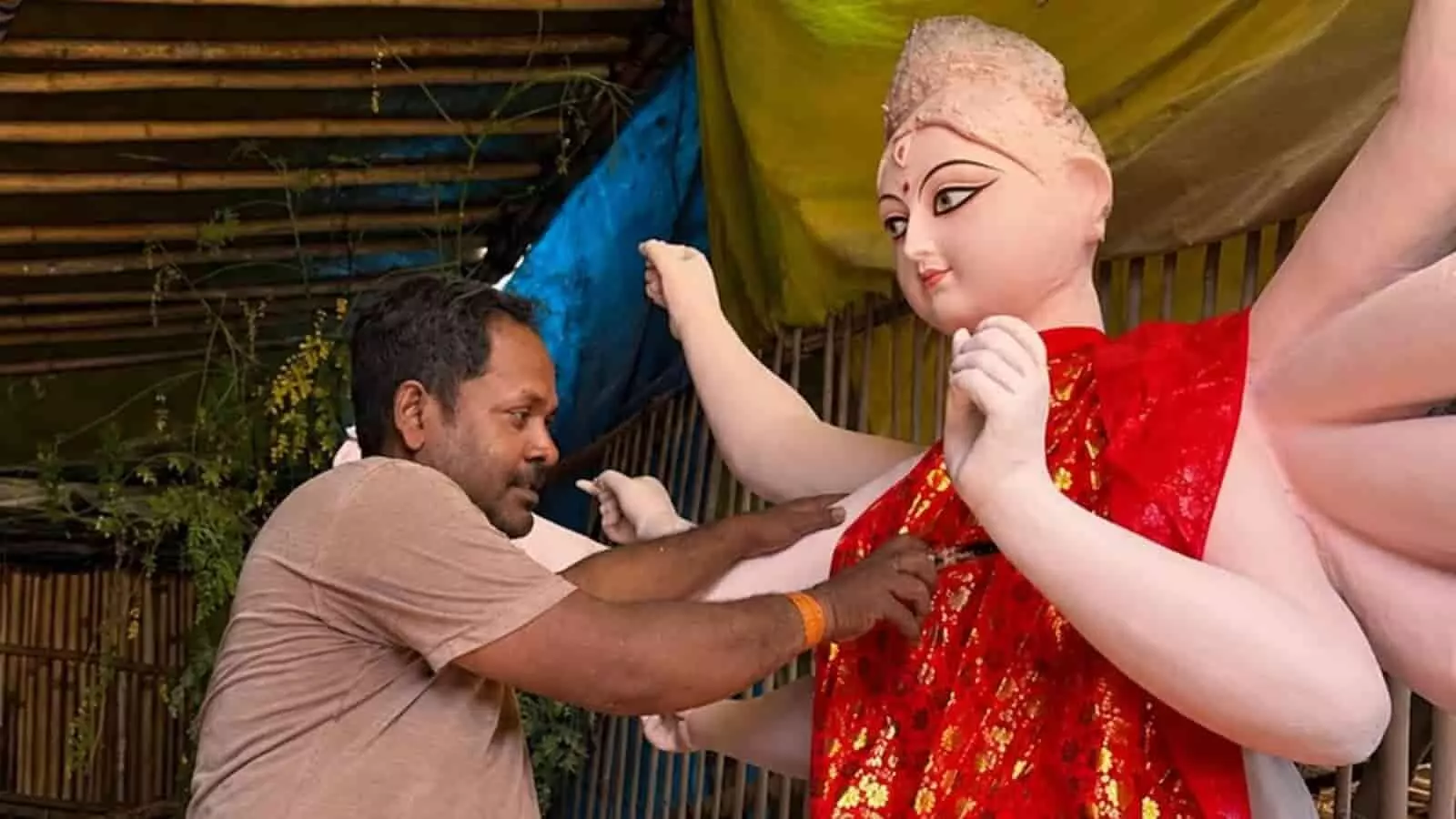 तस्वीर में बाएं तरफ एक कारीगर पंडाल में मां दुर्गा की मूर्ति बनाते हुए नजर आ रहा है. तस्वीर में बाएं तरफ एक कारीगर पंडाल में मां दुर्गा की मूर्ति बनाते हुए नजर आ रहा है.