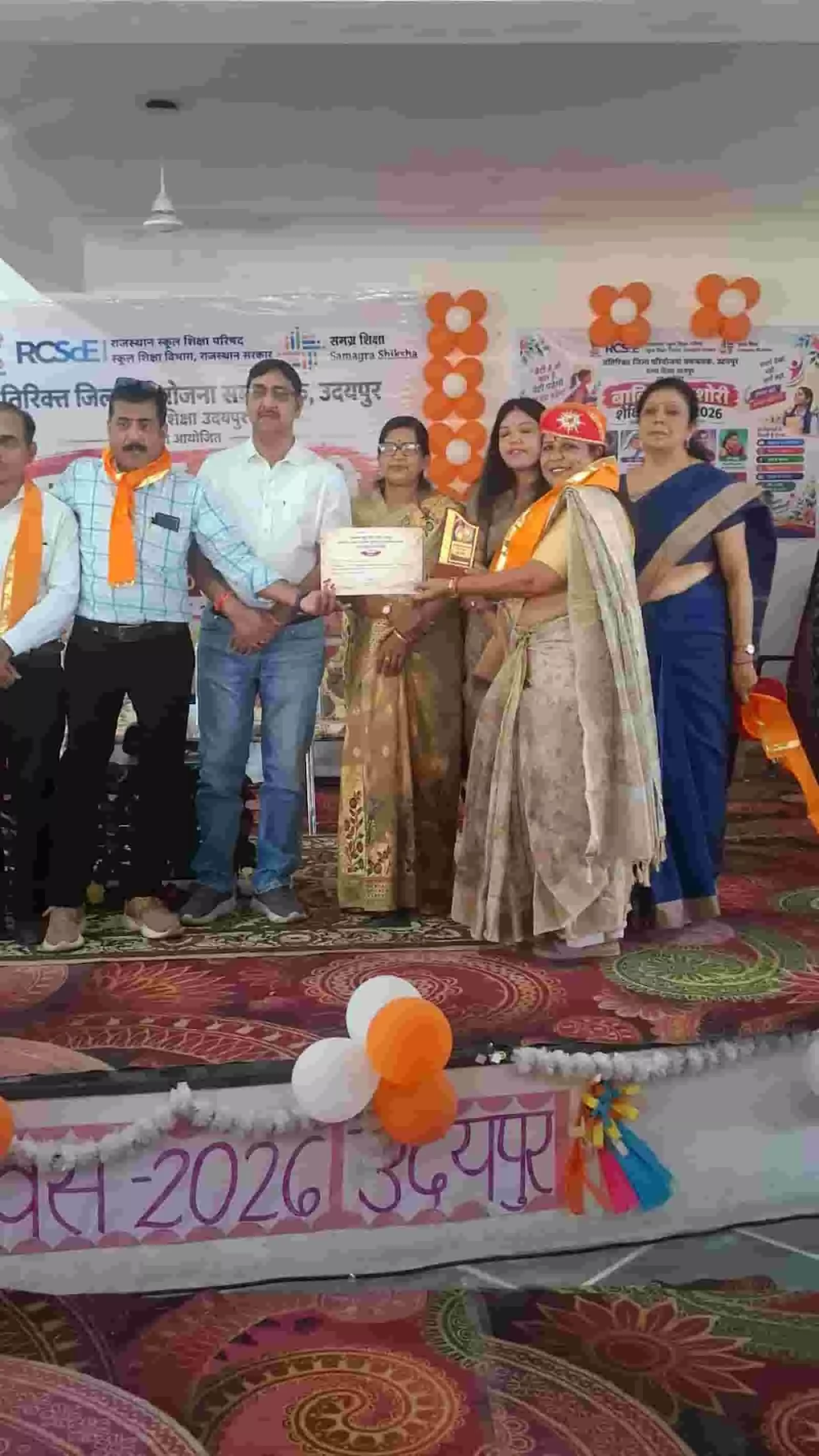 उदयपुर में जिला स्तरीय बालिका शैक्षिक मेले के मंच पर प्रमाण पत्र और स्मृति चिन्ह ग्रहण करती शिक्षिका और छात्राएं। उदयपुर में जिला स्तरीय बालिका शैक्षिक मेले के मंच पर प्रमाण पत्र और स्मृति चिन्ह ग्रहण करती शिक्षिका और छात्राएं।