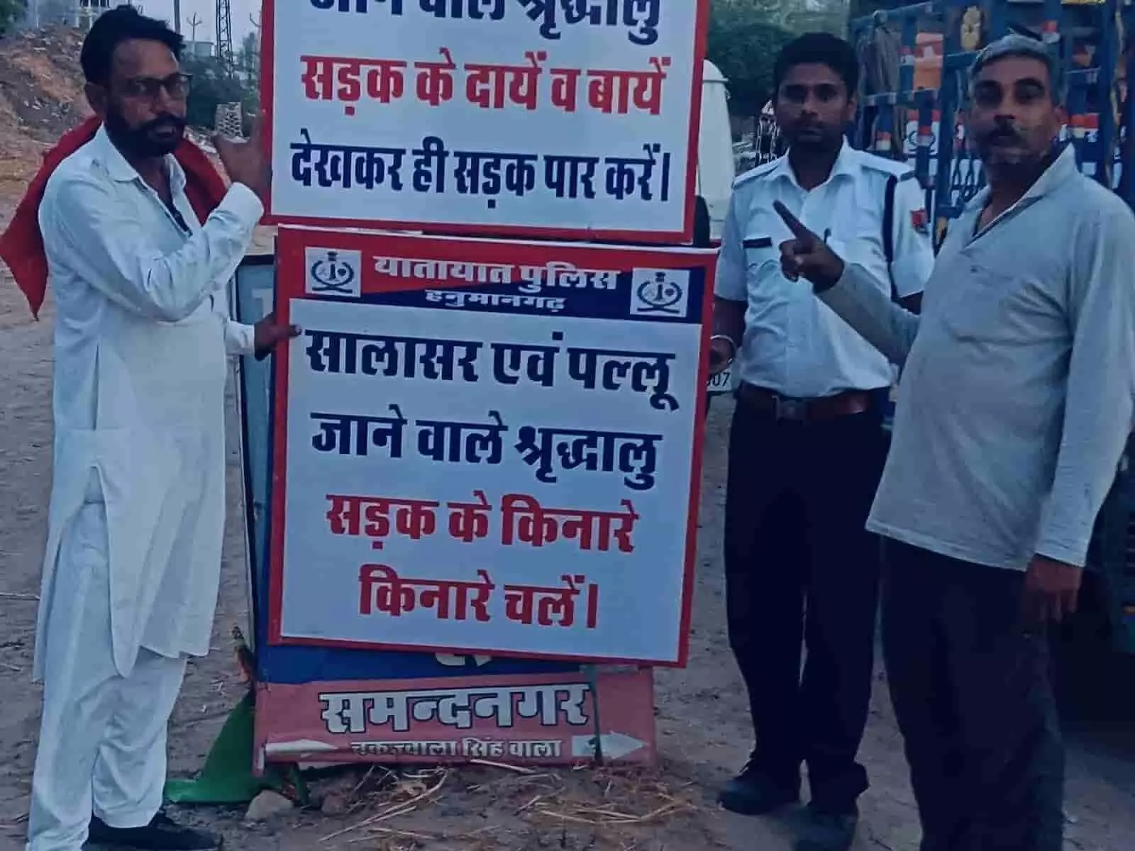तस्वीर में ट्रैफिक पुलिसकर्मी और दो नागरिक सड़क सुरक्षा बोर्ड के पास इशारा कर रहे हैं। तस्वीर में ट्रैफिक पुलिसकर्मी और दो नागरिक सड़क सुरक्षा बोर्ड के पास इशारा कर रहे हैं।