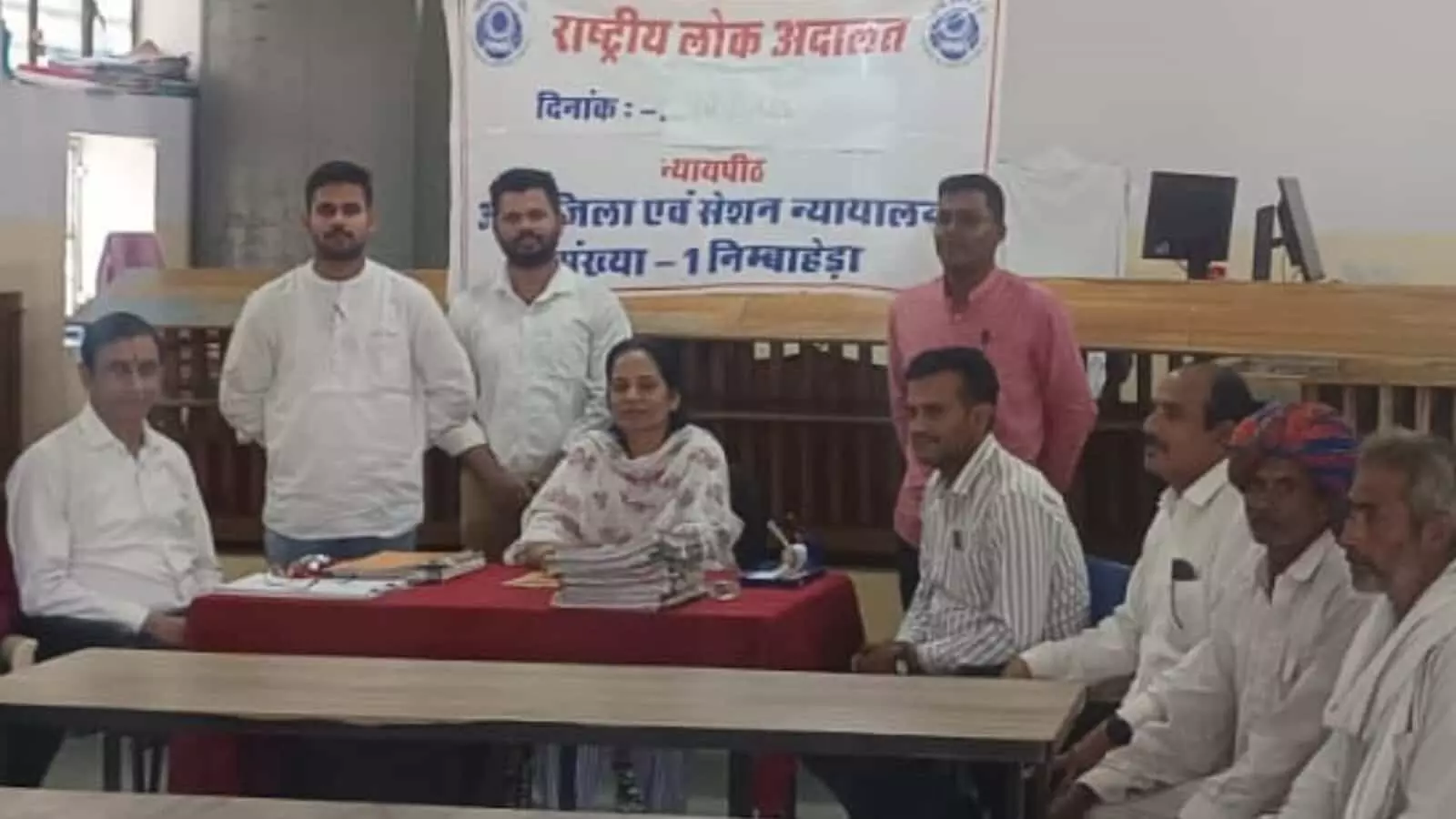 तस्वीर में राष्ट्रीय लोक अदालत के बैनर के सामने अधिकारी, अधिवक्ता और पक्षकार मेज के पास बैठे दिख रहे हैं। तस्वीर में राष्ट्रीय लोक अदालत के बैनर के सामने अधिकारी, अधिवक्ता और पक्षकार मेज के पास बैठे दिख रहे हैं।