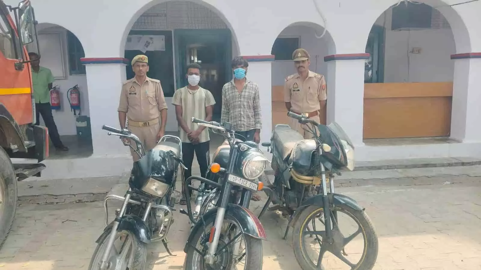 थाना परिसर में दो पुलिसकर्मियों के बीच खड़े दो आरोपी और उनके सामने रखी तीन मोटरसाइकिलें। थाना परिसर में दो पुलिसकर्मियों के बीच खड़े दो आरोपी और उनके सामने रखी तीन मोटरसाइकिलें।