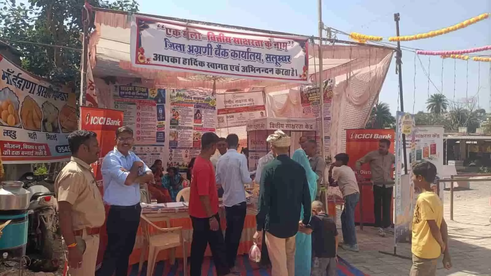 तस्वीर में सलूम्बर में वित्तीय साक्षरता शिविर पंडाल के पास खड़े लोग दिख रहे हैं। तस्वीर में सलूम्बर में वित्तीय साक्षरता शिविर पंडाल के पास खड़े लोग दिख रहे हैं।