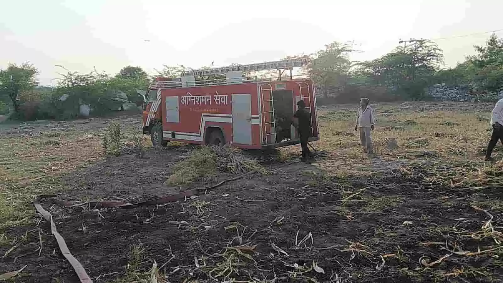 तस्वीर में खेत में खड़ी दमकल और आग बुझाते कर्मी दिख रहे हैं। तस्वीर में खेत में खड़ी दमकल और आग बुझाते कर्मी दिख रहे हैं।