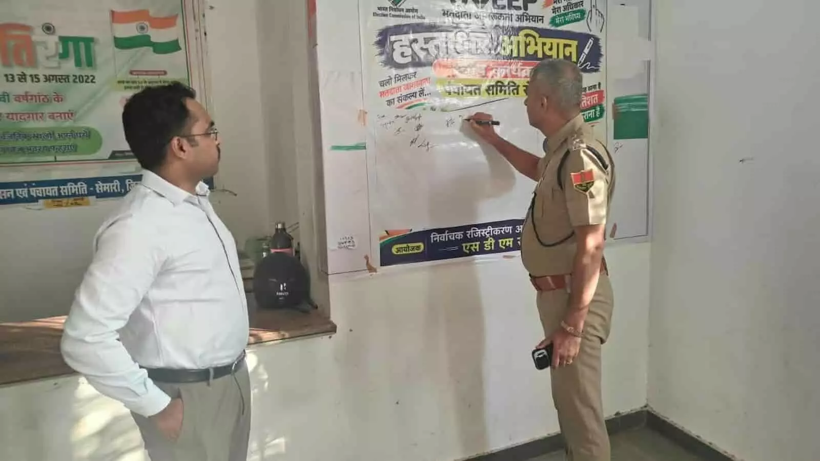 तस्वीर में स्वीप बैनर पर हस्ताक्षर करते पुलिस अधिकारी और पास खड़े जिला कलेक्टर। तस्वीर में स्वीप बैनर पर हस्ताक्षर करते पुलिस अधिकारी और पास खड़े जिला कलेक्टर।