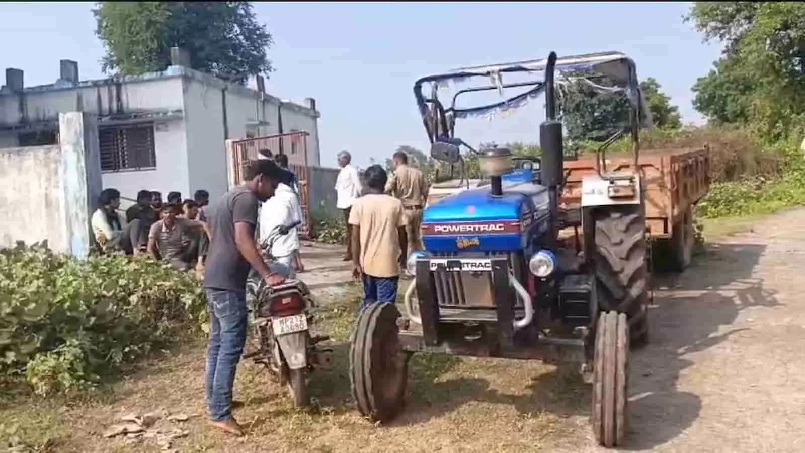 तस्वीर में गांव में एक नीले रंग के ट्रैक्टर और मकान के बाहर पुलिसकर्मी और स्थानीय लोग खड़े दिख रहे हैं। तस्वीर में गांव में एक नीले रंग के ट्रैक्टर और मकान के बाहर पुलिसकर्मी और स्थानीय लोग खड़े दिख रहे हैं।