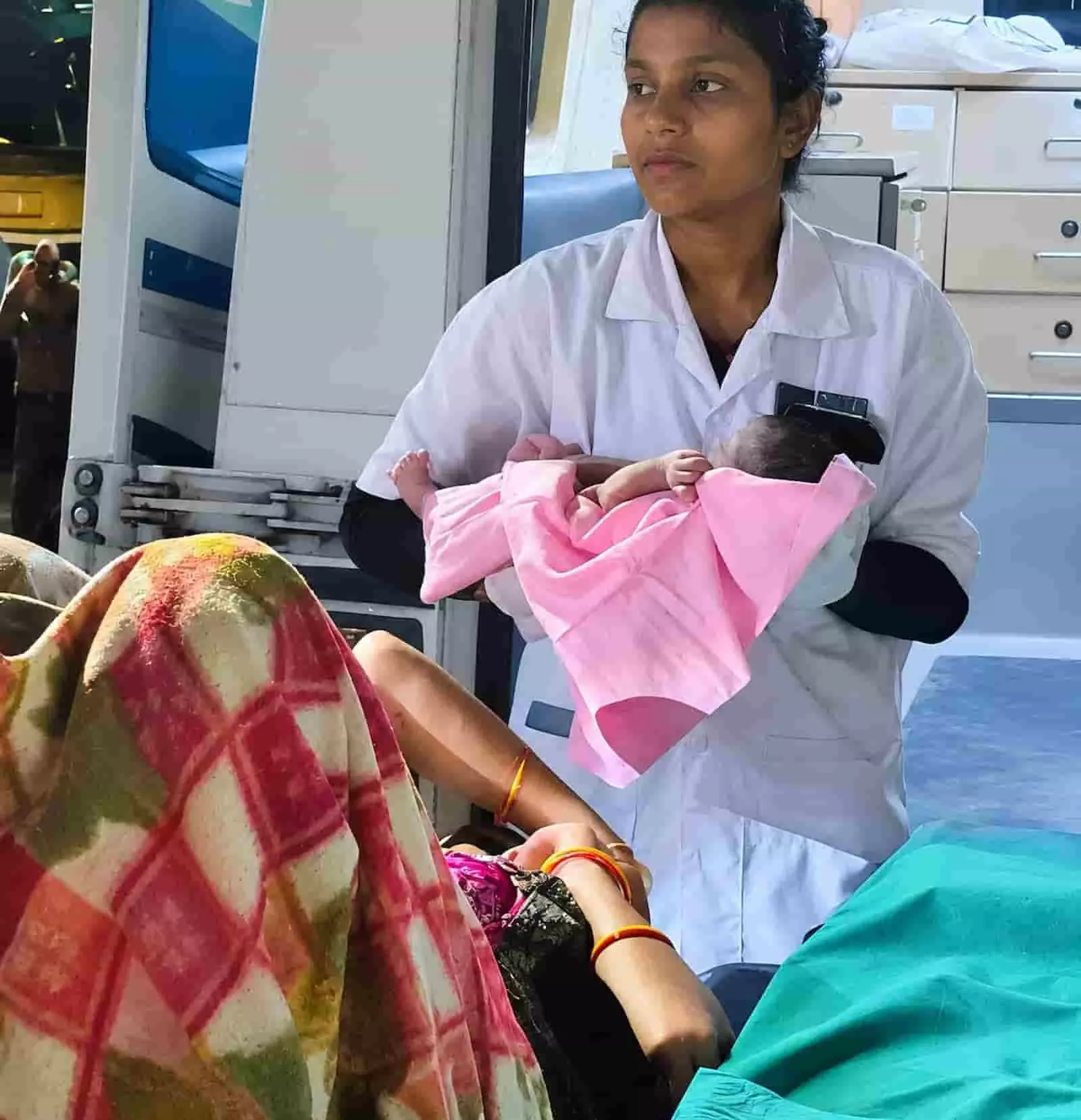 तस्वीर में दिख रही स्वास्थ्यकर्मी नवजात शिशु को गोद में लिए एम्बुलेंस में देखभाल कर रही है। तस्वीर में दिख रही स्वास्थ्यकर्मी नवजात शिशु को गोद में लिए एम्बुलेंस में देखभाल कर रही है।