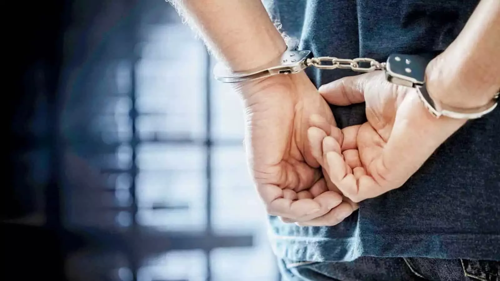 हथकड़ी पहने हुए आरोपी व्यक्ति को पुलिस हिरासत के दौरान दिखाया गया है। हथकड़ी पहने हुए आरोपी व्यक्ति को पुलिस हिरासत के दौरान दिखाया गया है।