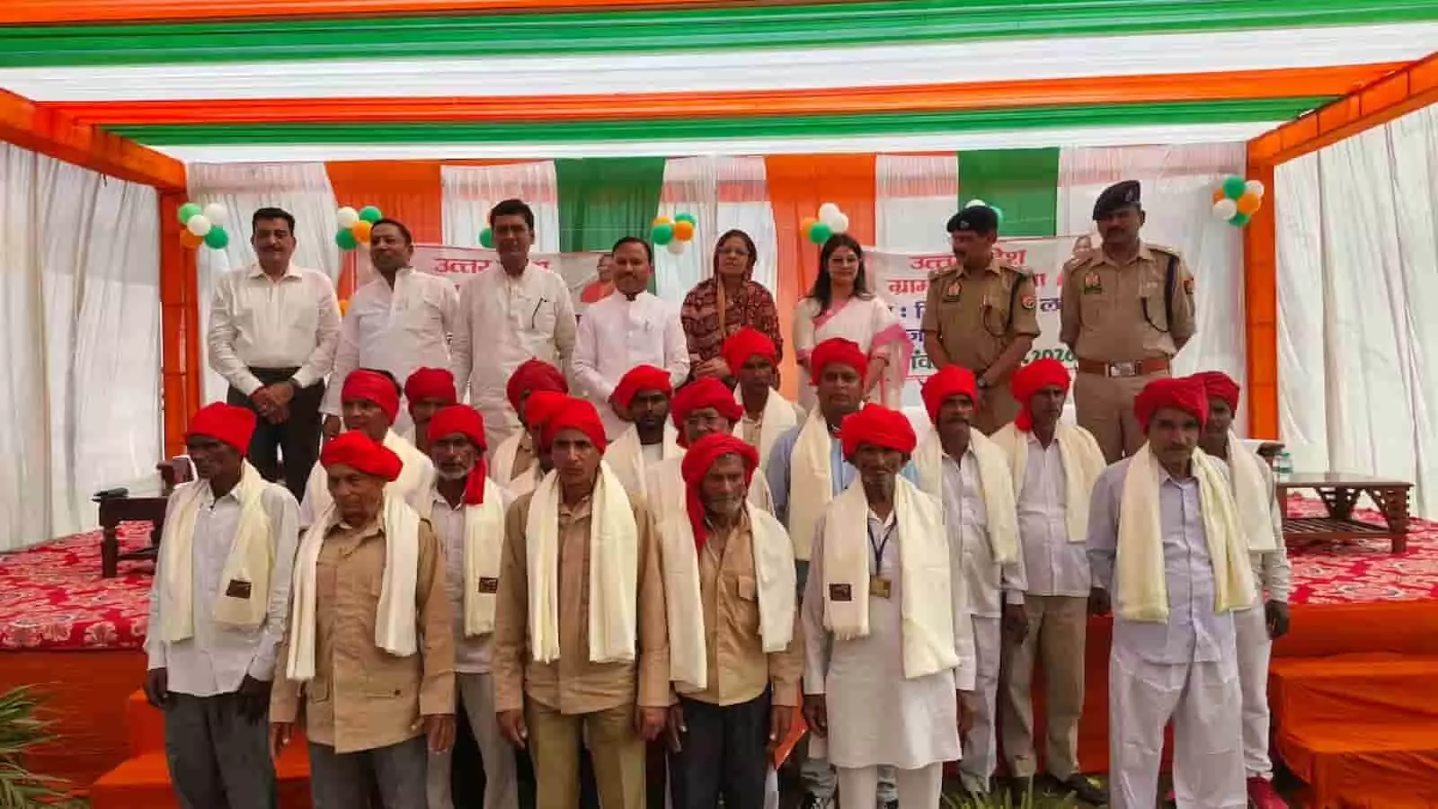तस्वीर में लाल पगड़ी पहने ग्राम प्रहरी प्रशासनिक अधिकारियों के साथ मंच के सामने खड़े हैं। तस्वीर में लाल पगड़ी पहने ग्राम प्रहरी प्रशासनिक अधिकारियों के साथ मंच के सामने खड़े हैं।