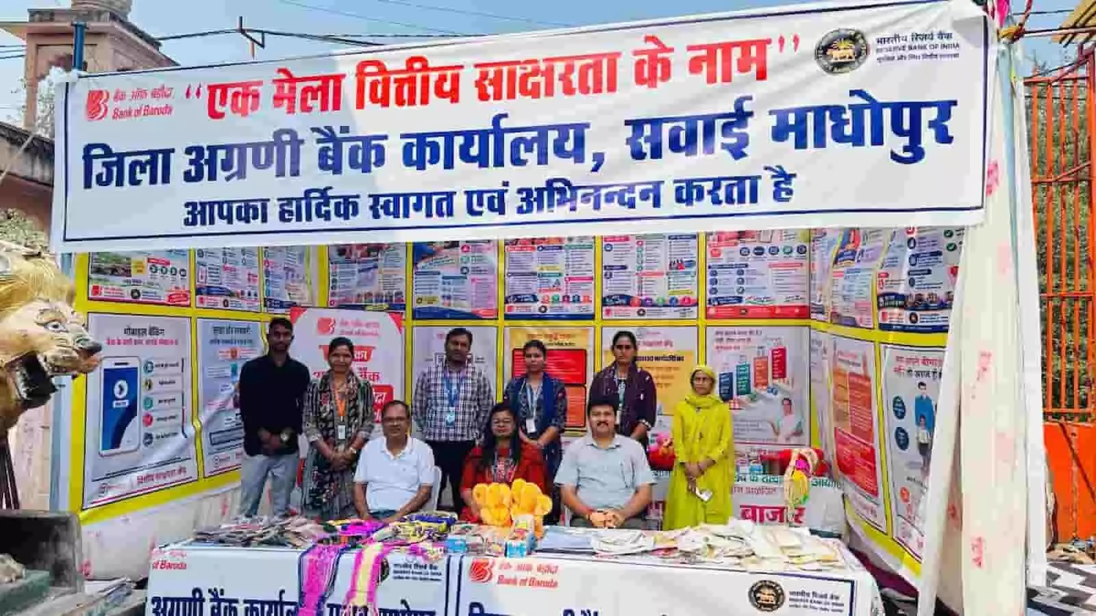 तस्वीर में वित्तीय साक्षरता शिविर के दौरान सवाई माधोपुर में बैनर के आगे खड़े बैंक अधिकारी दिख रहे हैं। तस्वीर में वित्तीय साक्षरता शिविर के दौरान सवाई माधोपुर में बैनर के आगे खड़े बैंक अधिकारी दिख रहे हैं।