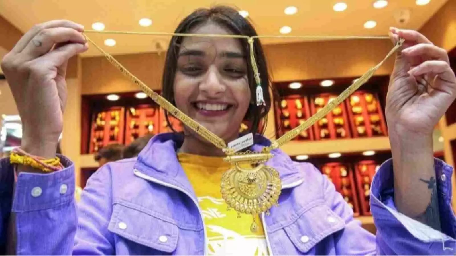 दुकान के अंदर सोने का हार दिखाती महिला ग्राहक सोने और चांदी की घटी कीमतों के संदर्भ में। दुकान के अंदर सोने का हार दिखाती महिला ग्राहक सोने और चांदी की घटी कीमतों के संदर्भ में।