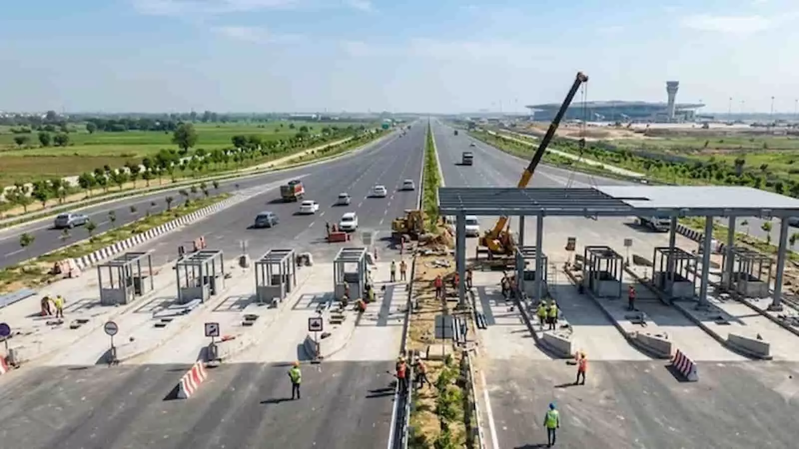 तस्वीर में ग्रीनफील्ड एक्सप्रेसवे पर निर्माणाधीन टोल प्लाजा और काम करते मजदूर दिखाई दे रहे हैं। तस्वीर में ग्रीनफील्ड एक्सप्रेसवे पर निर्माणाधीन टोल प्लाजा और काम करते मजदूर दिखाई दे रहे हैं।