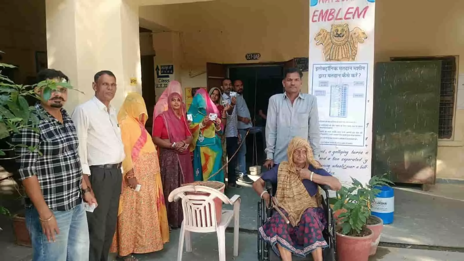तस्वीर में मतदान केंद्र के बाहर कतार में खड़े ग्रामीण मतदाता पहचान पत्र दिखाते हुए तस्वीर में मतदान केंद्र के बाहर कतार में खड़े ग्रामीण मतदाता पहचान पत्र दिखाते हुए