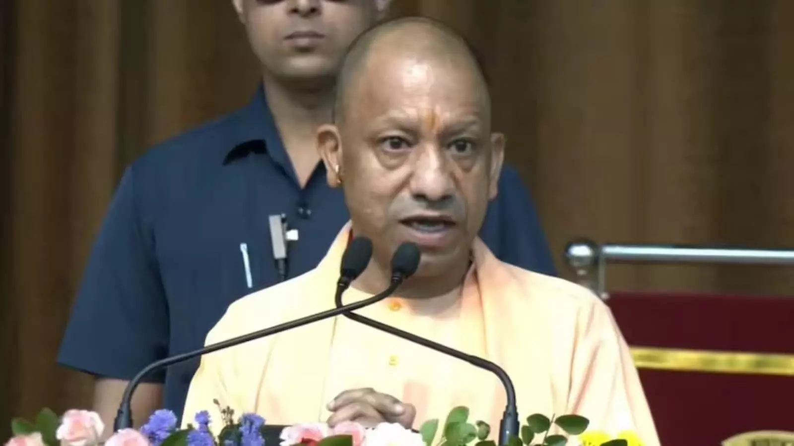 पोडियम पर लगे माइक के सामने बोलते हुए उत्तर प्रदेश के मुख्यमंत्री योगी आदित्यनाथ।