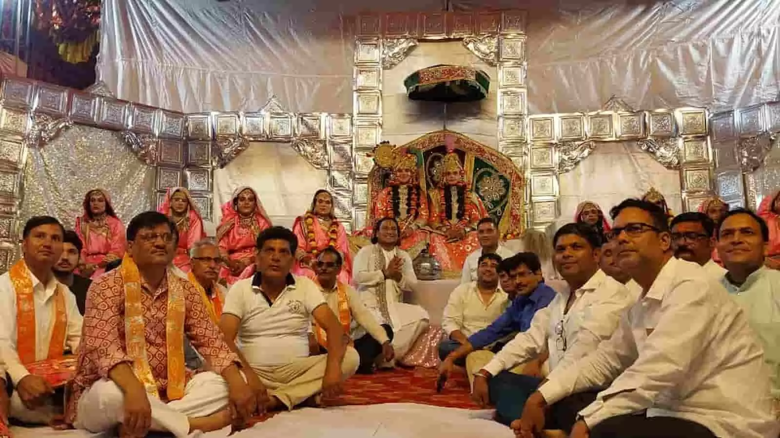 तस्वीर में डीग में आयोजित महारास लीला के मंच पर कलाकार और आयोजक समिति के लोग बैठे हैं।