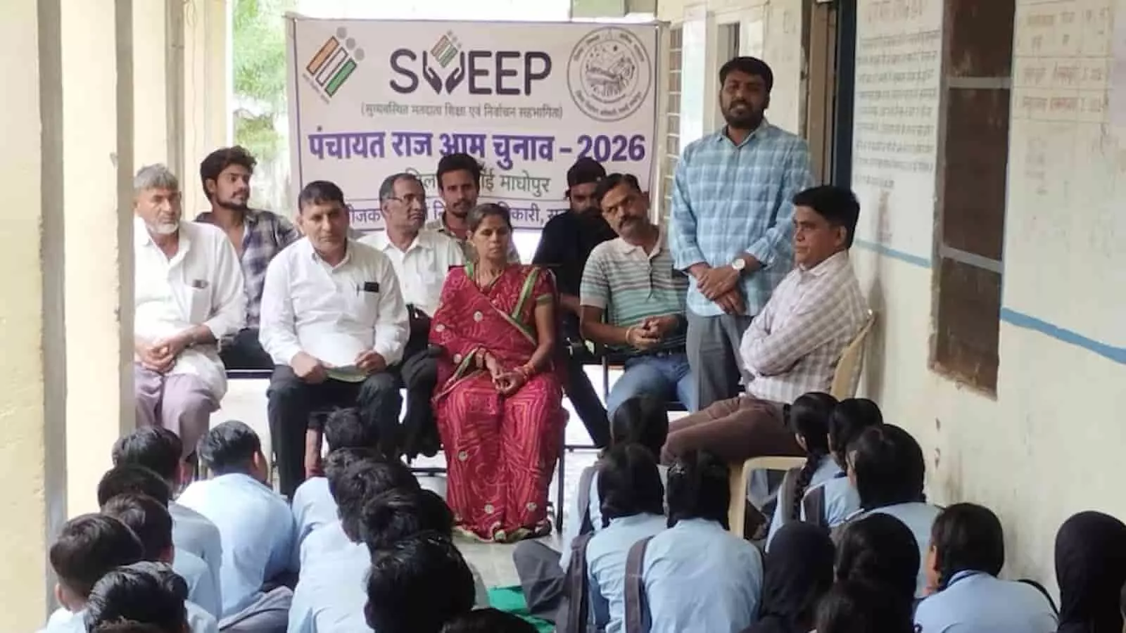 तस्वीर में पचीपल्या स्कूल में स्वीप बैनर के सामने आयोजित मतदाता जागरूकता कार्यक्रम में बैठे ग्रामीण और विद्यार्थी दिख रहे हैं। तस्वीर में पचीपल्या स्कूल में स्वीप बैनर के सामने आयोजित मतदाता जागरूकता कार्यक्रम में बैठे ग्रामीण और विद्यार्थी दिख रहे हैं।