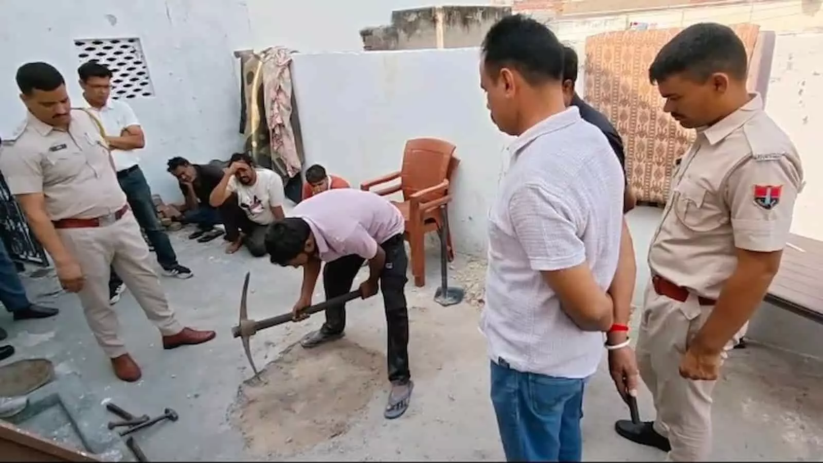 तस्वीर में पुलिसकर्मियों की मौजूदगी में एक व्यक्ति भीलवाड़ा के मकान की छत पर गेंती से खुदाई कर रहा है। तस्वीर में पुलिसकर्मियों की मौजूदगी में एक व्यक्ति भीलवाड़ा के मकान की छत पर गेंती से खुदाई कर रहा है।